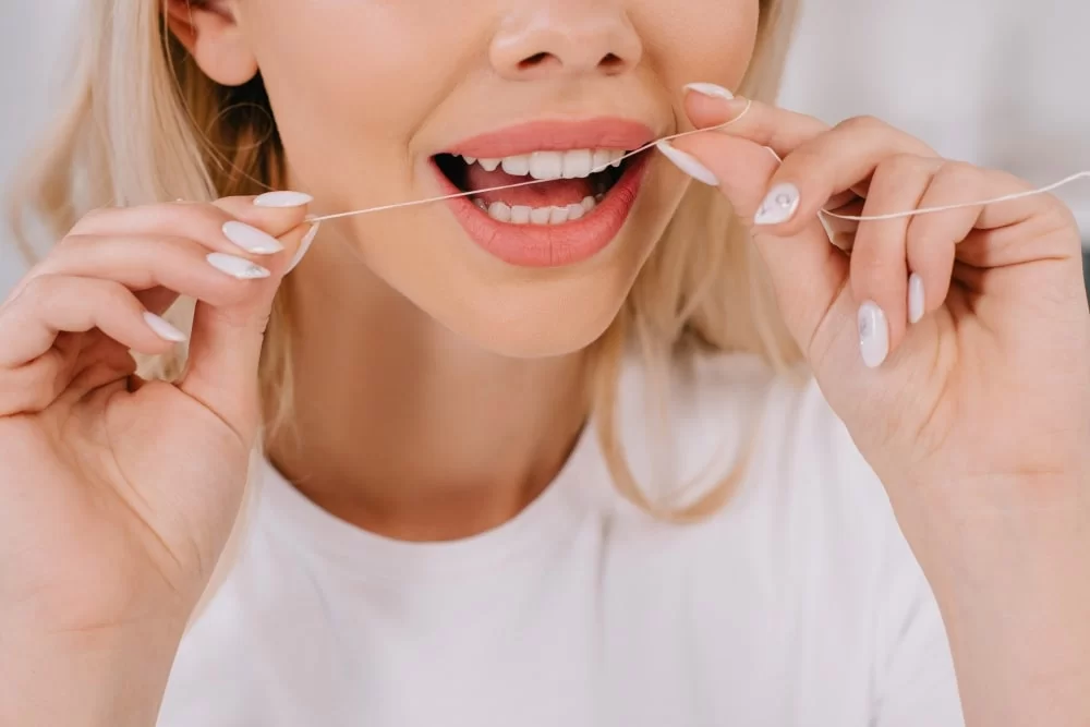 woman flossing teeth with dental floss